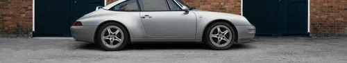 Porsche prateado estacionado diante de portas de madeira